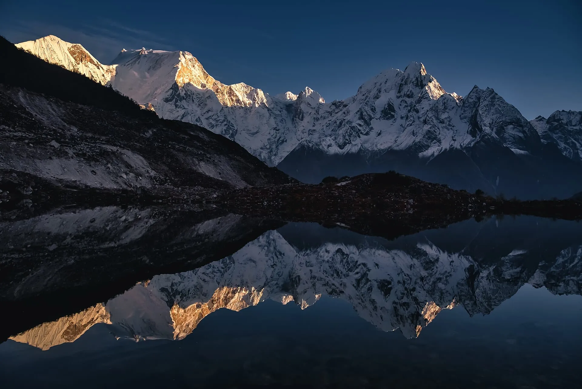 Golden light on the Manaslu range reflected in a still mountain lake